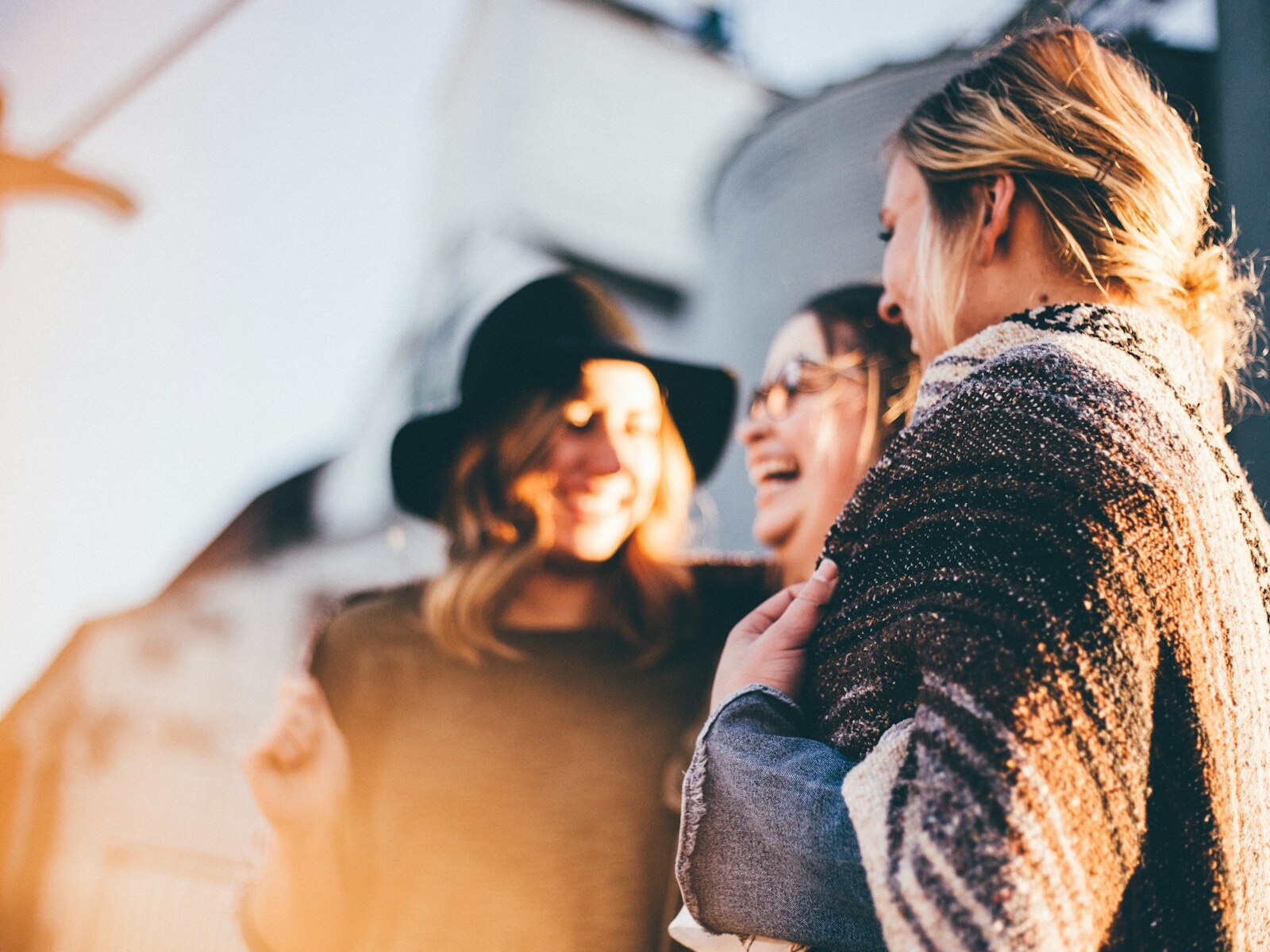Three friends laughing together outside in warm evening light